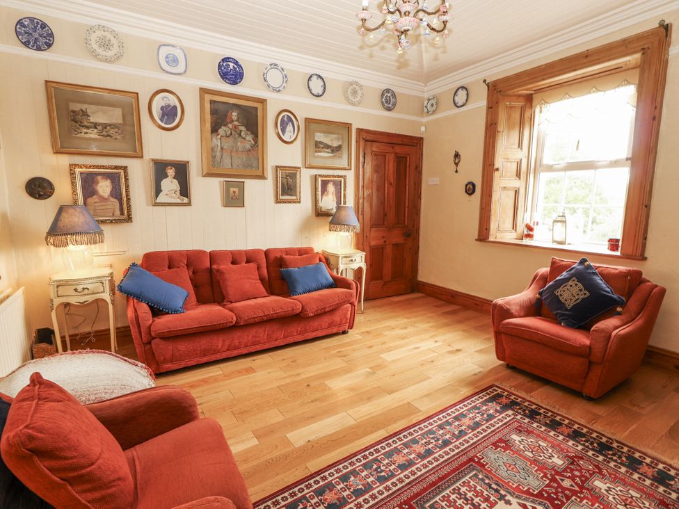 A living room with sofas, artwork on the walls and a window at White Heather Cottage in Killalou