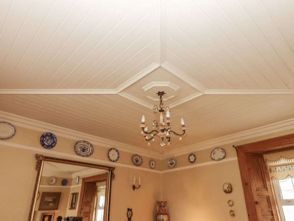 A living room with a chandelier and decorative plates at White Heather Cottage in Killalou