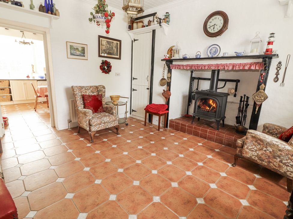 A living room with a fireplace and seating at White Heather Cottage in Killalou