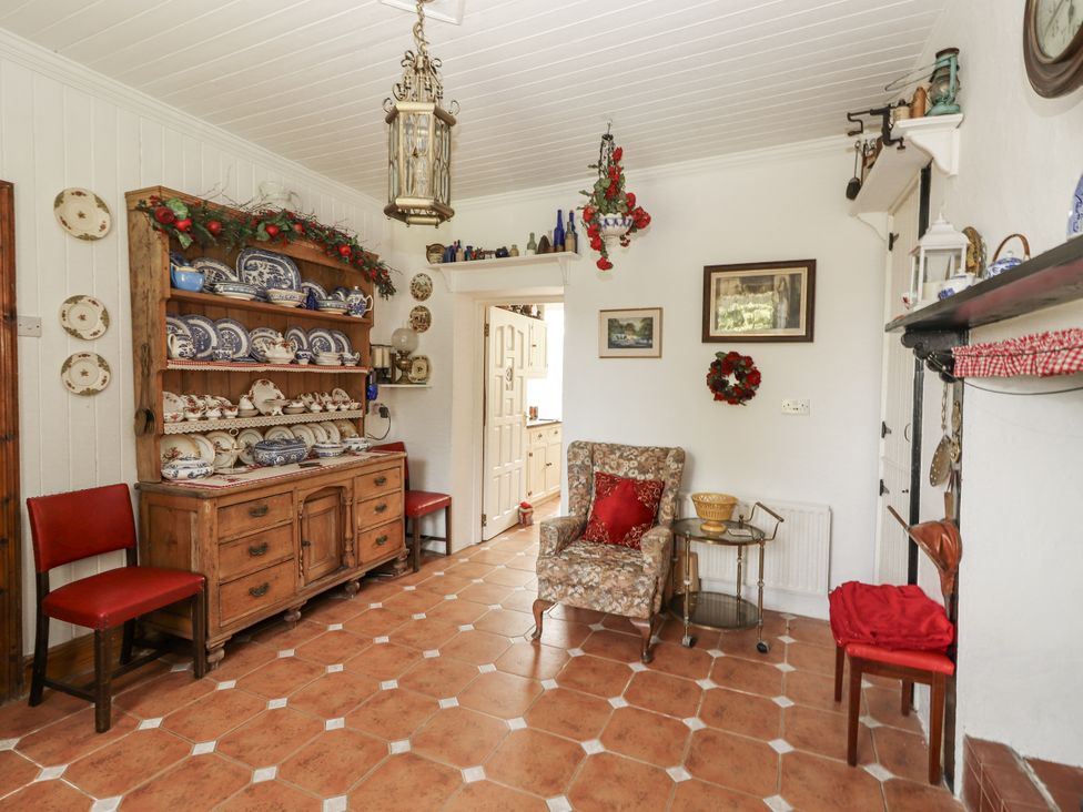 A dining room with a cabinet and chairs at White Heather Cottage in Killalou
