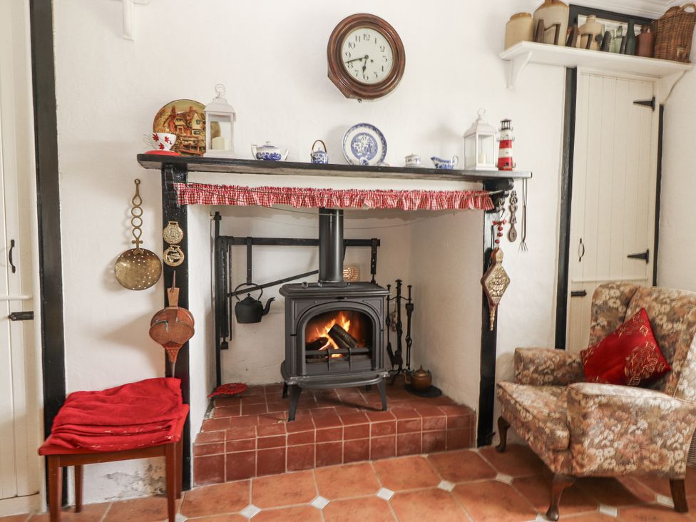 A living room with a fireplace and wooden stove at White Heather Cottage in Killalou