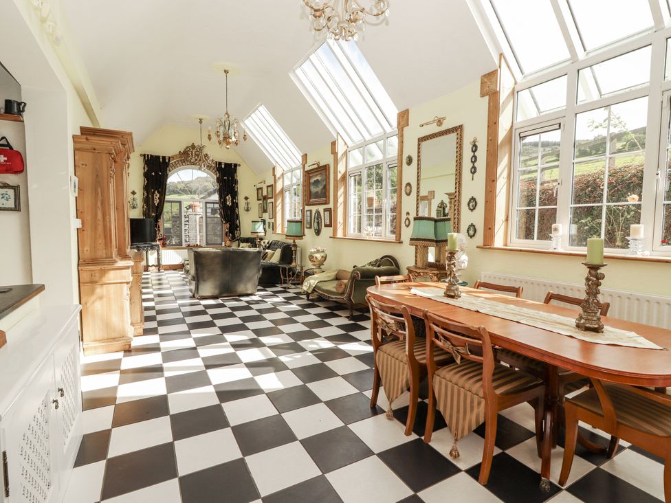 A conservatory with a dining table and chairs at White Heather Cottage in Killalou