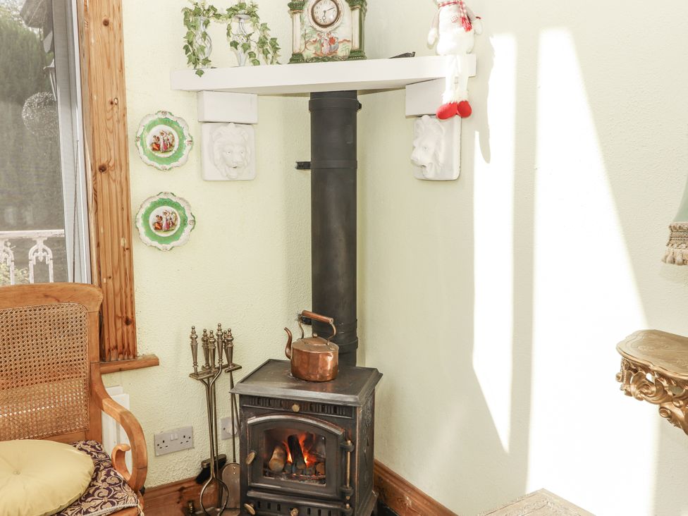 A sitting room with a wood stove and decorative items at White Heather Cottage in Killalou