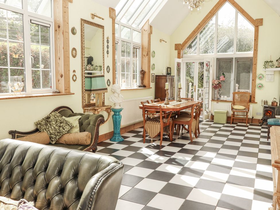 A conservatory with a table and chairs at White Heather Cottage in Killalou