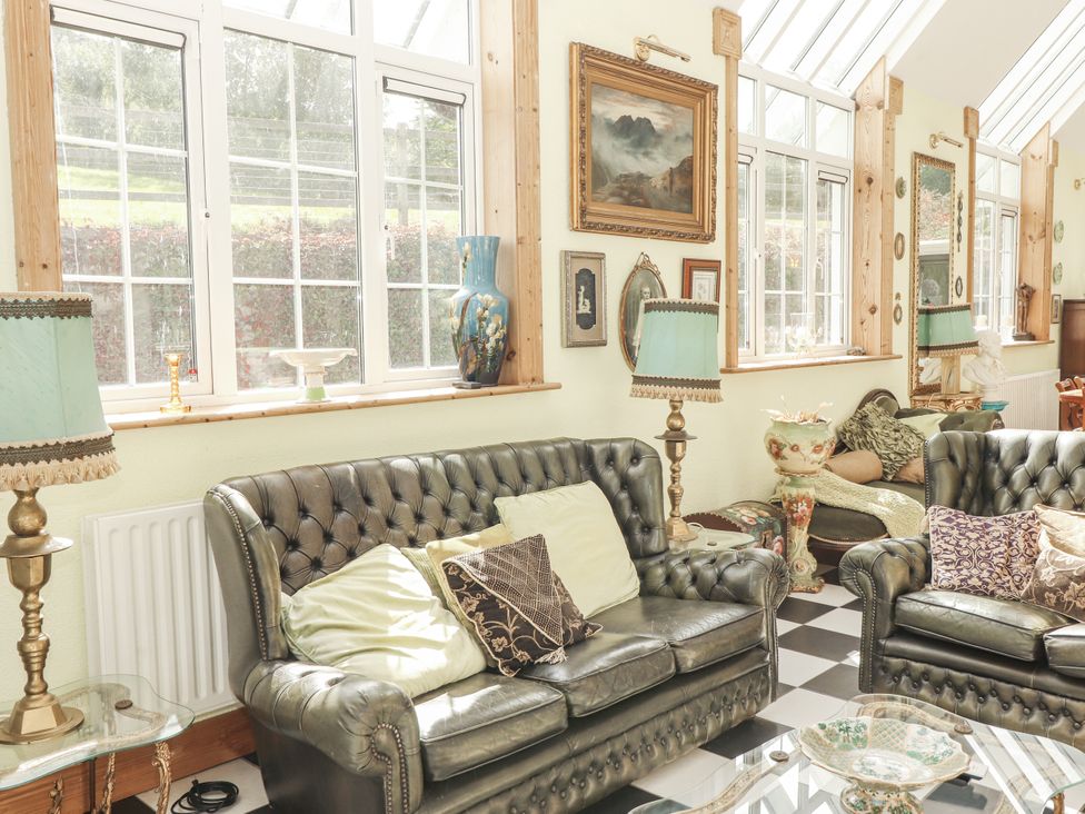 A conservatory with sofas and decorative items at White Heather Cottage Killalou