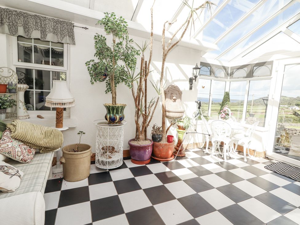 A conservatory with plants and seating at White Heather Cottage in Killalou
