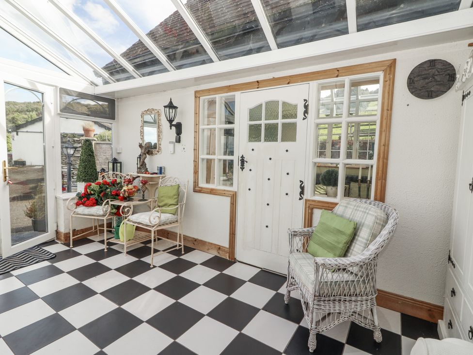 A conservatory with seating and plants at White Heather Cottage in Killalou