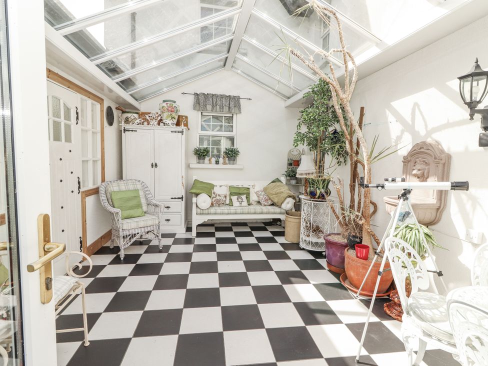 A conservatory with a sofa and telescope at White Heather Cottage in Killalou