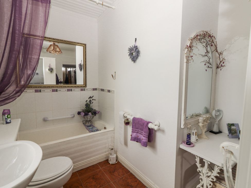 A bathroom with a bathtub and a sink at White Heather Cottage in Killalou