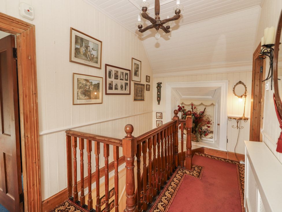 A hallway with a staircase and decorative pictures at White Heather Cottage in Killalou
