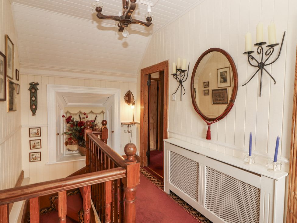 A hallway with a chandelier and mirror at White Heather Cottage in Killalou