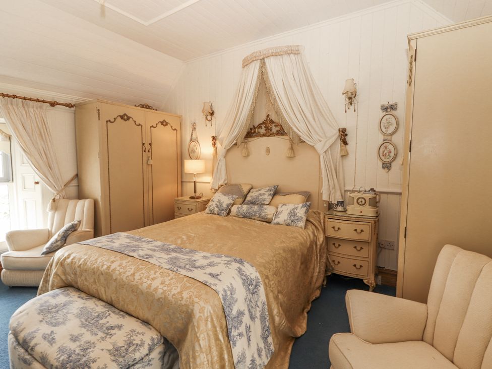 A bedroom with a bed and armchair at White Heather Cottage in Killalou