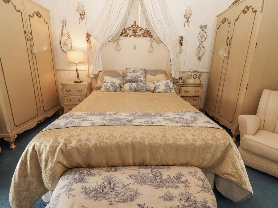 A bedroom with a bed and wardrobes at White Heather Cottage in Killalou