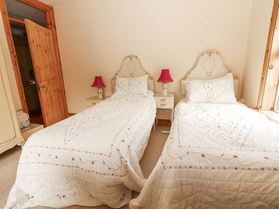 A bedroom with twin beds and bedside tables at White Heather Cottage in Killalou