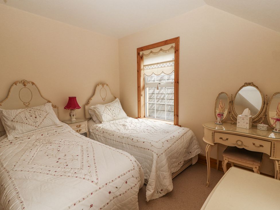 A bedroom with two beds and a dresser at White Heather Cottage in Killalou