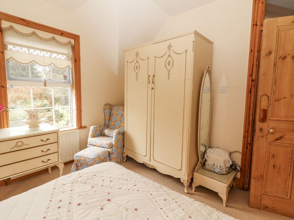 A bedroom with a wardrobe and dresser at White Heather Cottage in Killalou