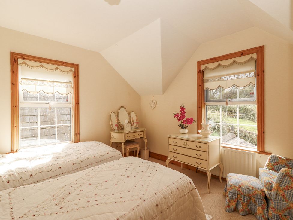 A bedroom with two beds and a dresser at White Heather Cottage in Killalou