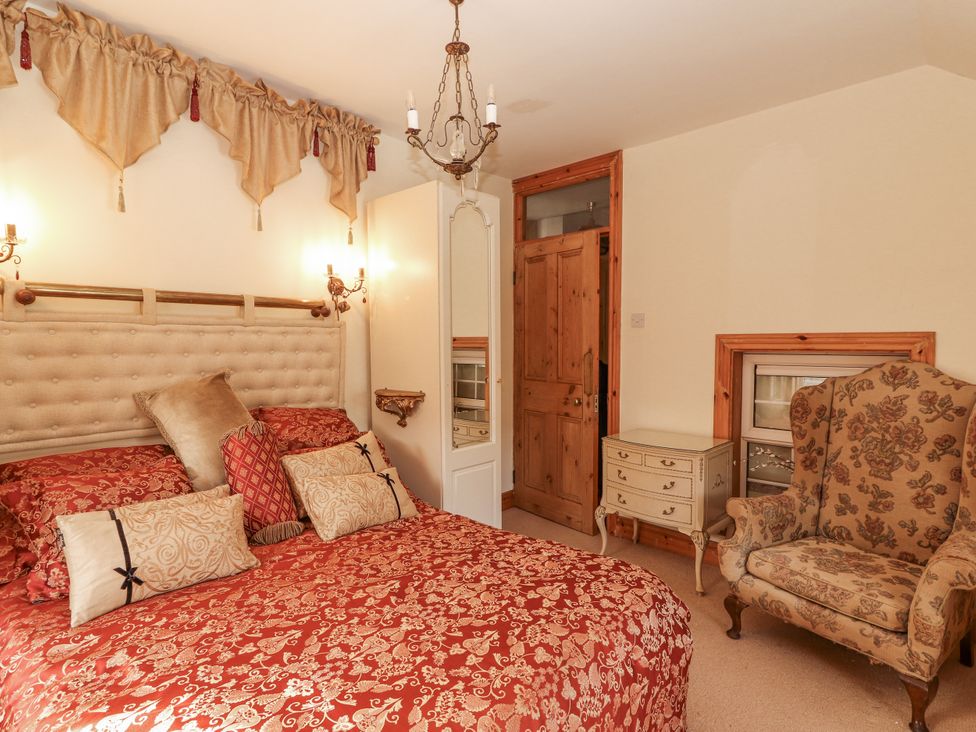 A bedroom with a bed, dresser, and armchair at White Heather Cottage in Killalou