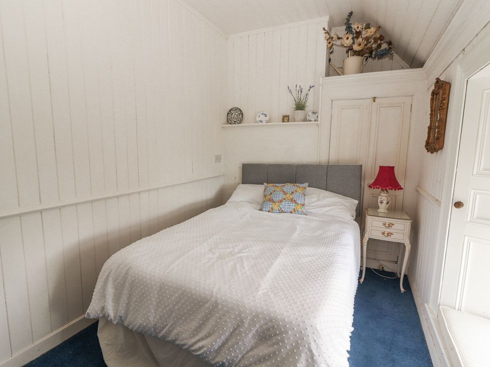 A bedroom with a bed and nightstand at White Heather Cottage in Killalou