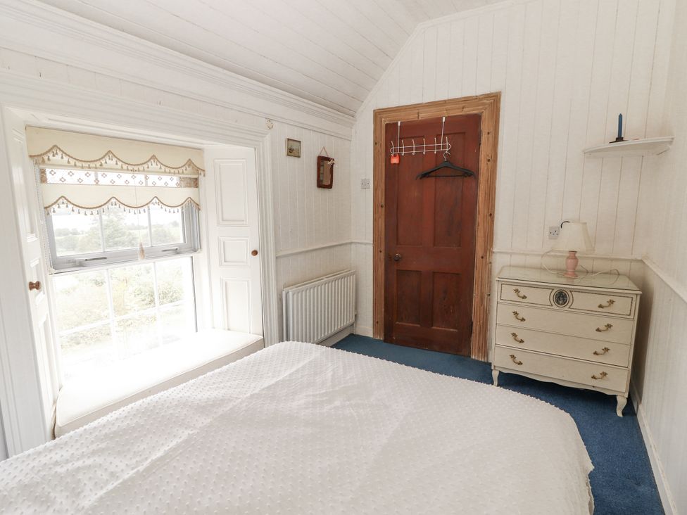 A bedroom with a window and a door at White Heather Cottage Killalou