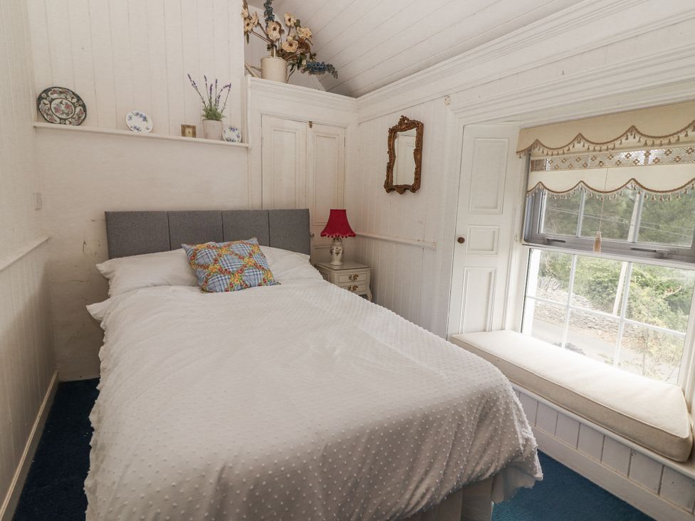 A bedroom with a bed and window seat at White Heather Cottage in Killalou