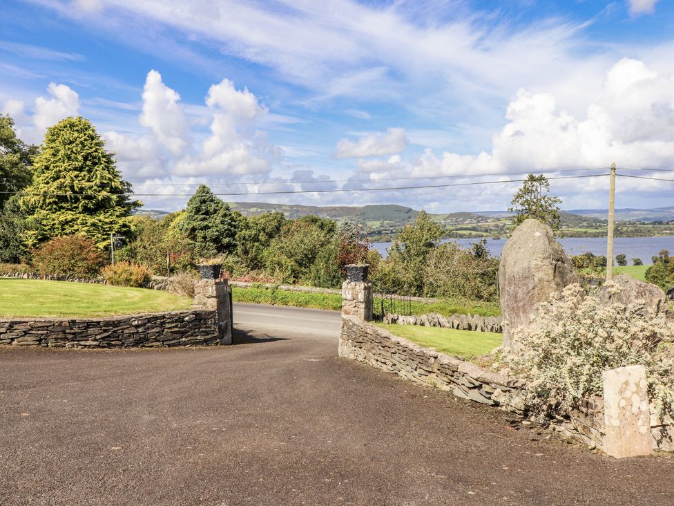 A view of a lake with trees and stone walls at White Heather Cottage in Killalou
