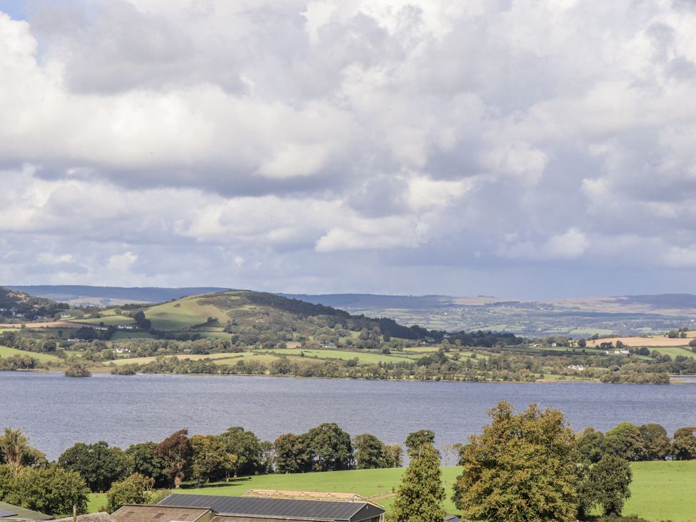 A view of a lake surrounded by hills and trees at White Heather Cottage in Killalou