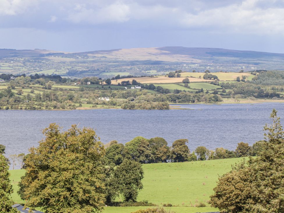 A landscape view featuring a lake surrounded by trees and fields at White Heather Cottage in Killalou