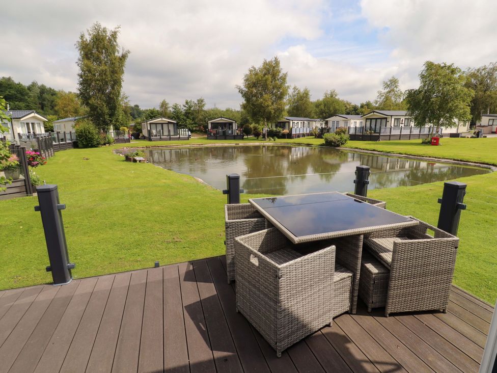 An outdoor area with a table and chairs overlooking a pond at 22 Yealand Carnforth