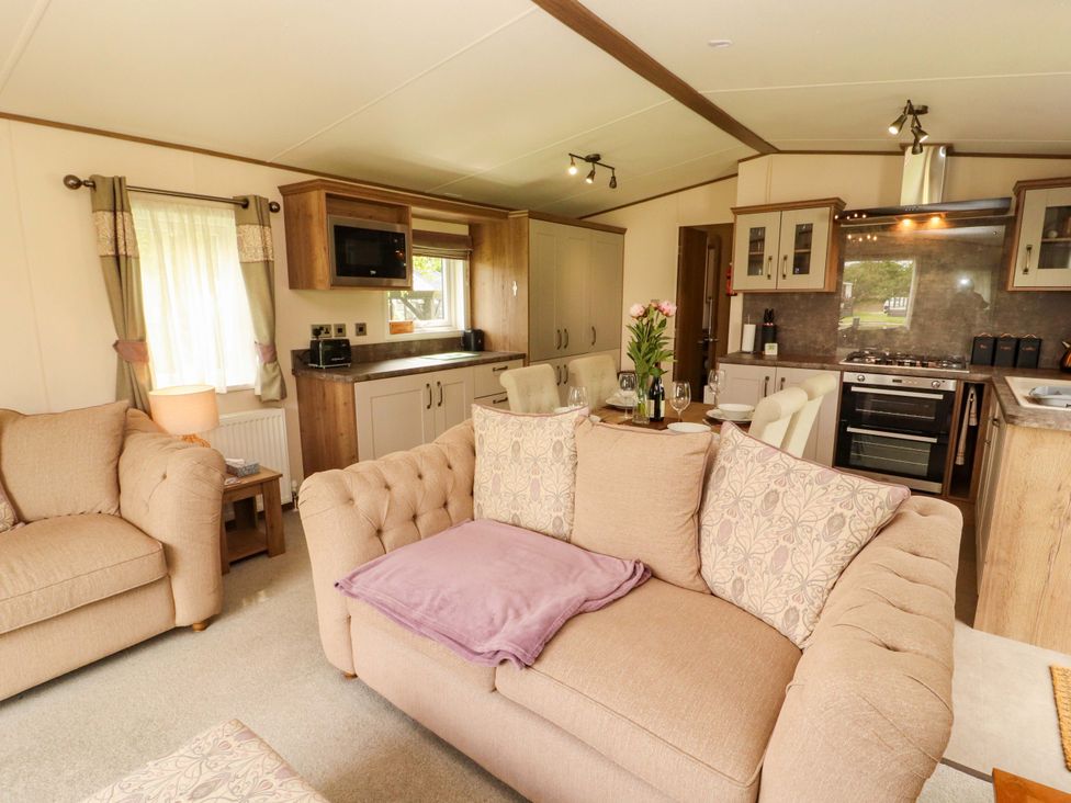 A living room with a sofa and kitchen area at 22 Yealand in Carnforth