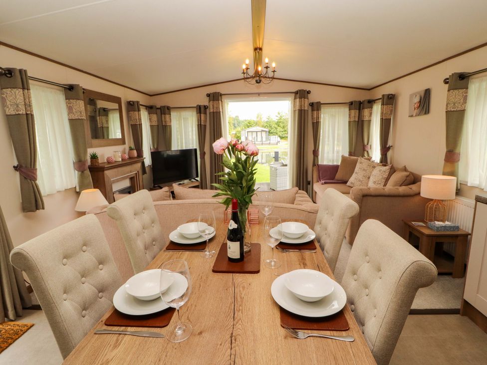 A dining table with chairs and flowers at 22 Yealand in Carnforth