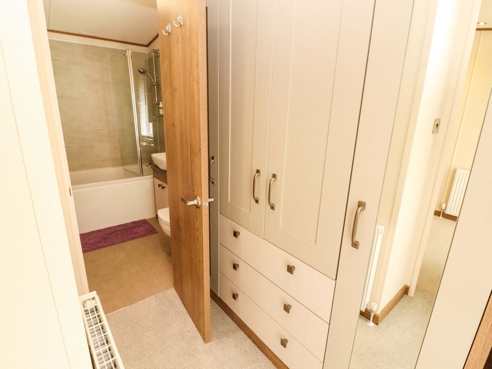 A bathroom with a bathtub, shower, and storage cabinet at 22 Yealand in Carnforth