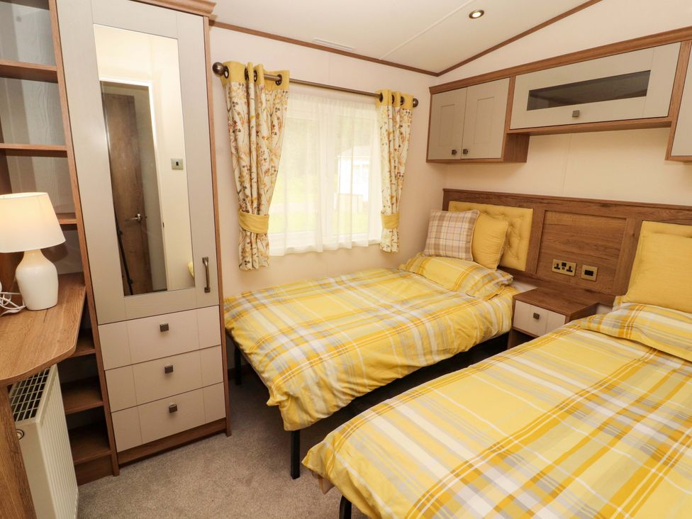 A bedroom with two beds and a wardrobe at 22 Yealand in Carnforth
