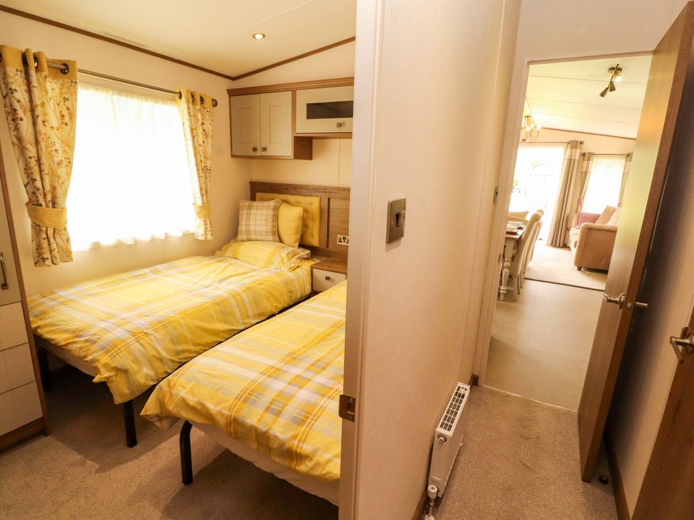 A bedroom with two beds and curtains at 22 Yealand in Carnforth