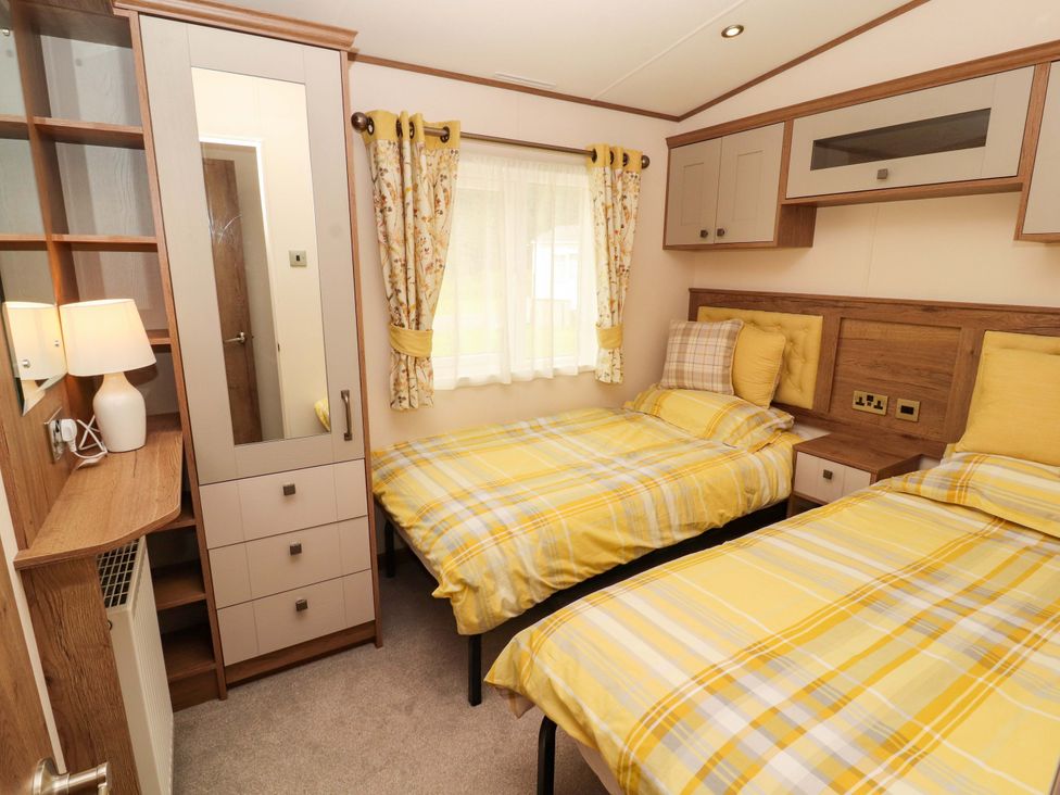 A bedroom with two beds and a wardrobe at 22 Yealand in Carnforth