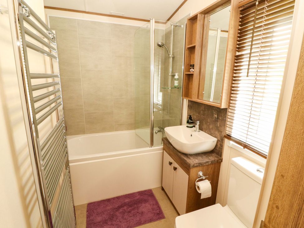 A bathroom with a bathtub, shower, and washbasin at 22 Yealand, Carnforth