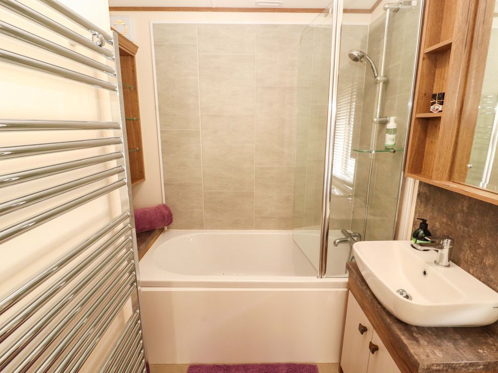 A bathroom with a bathtub, shower, and sink at 22 Yealand in Carnforth