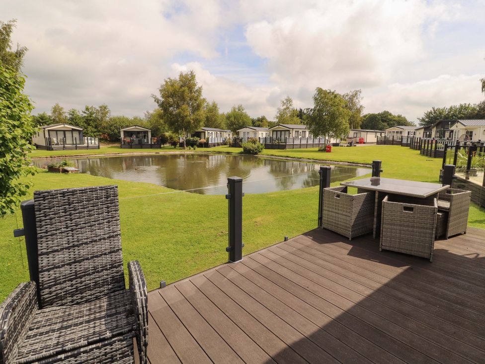 An outdoor area with a table and chairs overlooking a pond at 22 Yealand in Carnforth