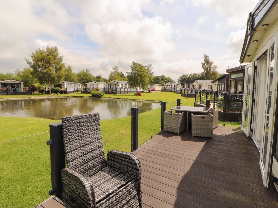 An outdoor area with chairs, table, and a pond at 22 Yealand in Carnforth