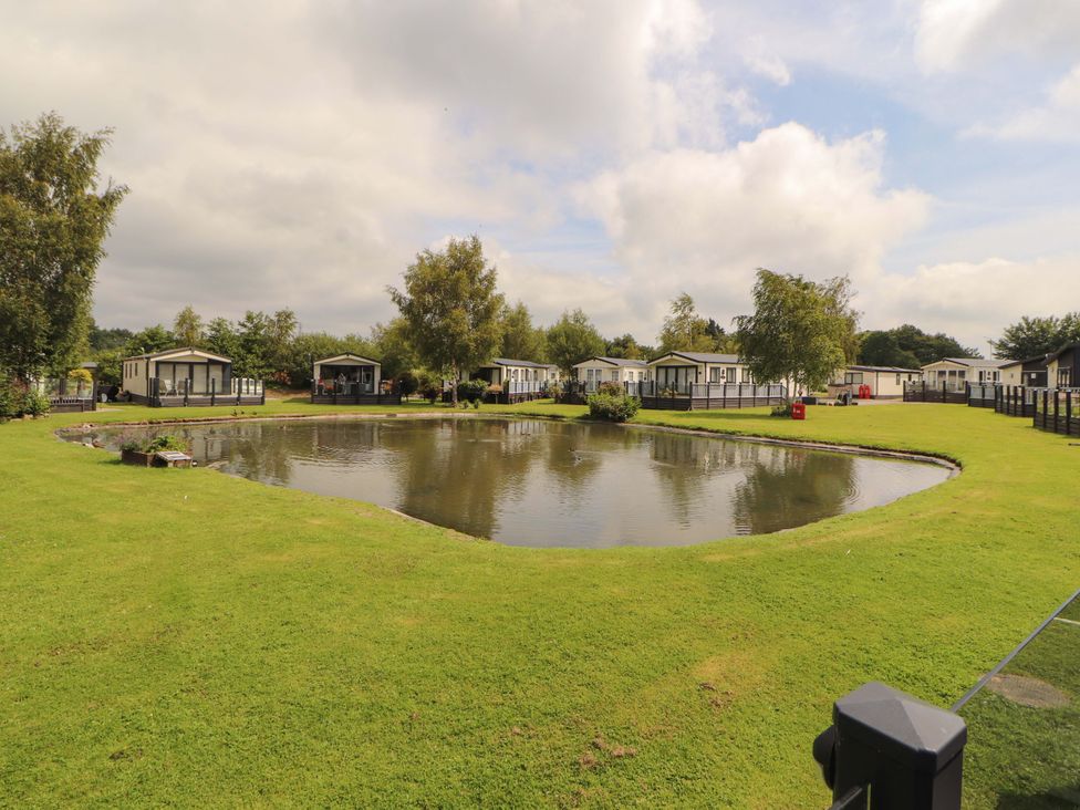 An outdoor area with a pond and mobile homes at 22 Yealand in Carnforth