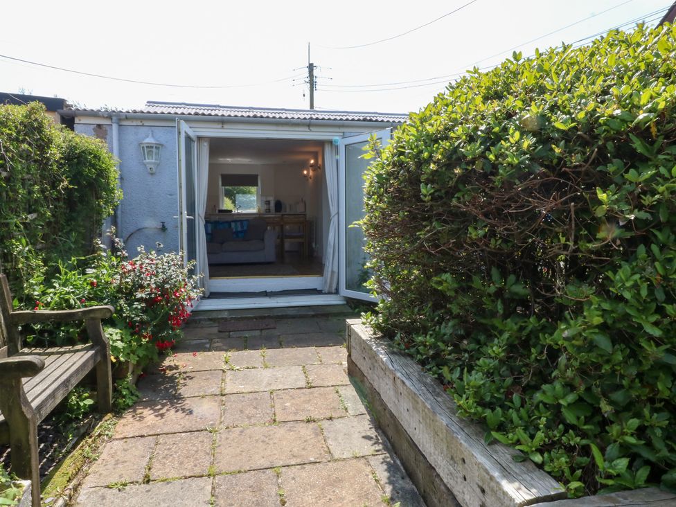 A garden with a pathway and seating area at Hafan Bach in Abersoch