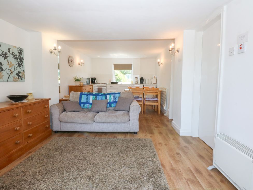 A living room with a sofa and dining area at Hafan Bach in Abersoch
