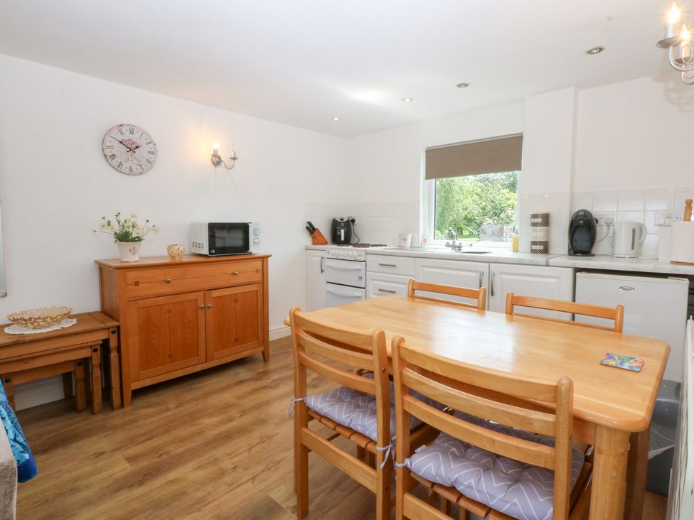 A kitchen with a table and chairs at Hafan Bach in Abersoch