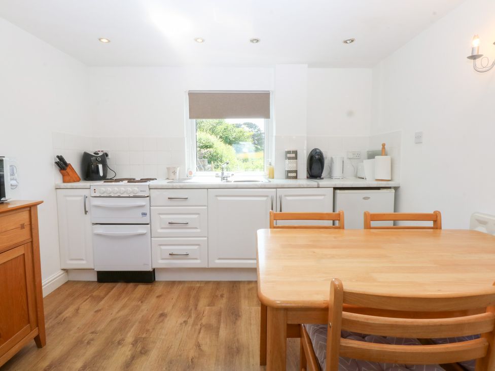 A kitchen with a table and chairs at Hafan Bach in Abersoch