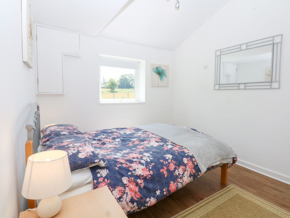 A bedroom with a bed and lamp at Hafan Bach in Abersoch