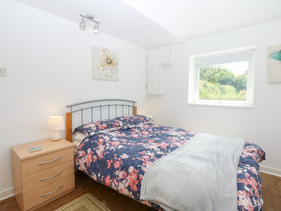 A bedroom with a bed and side table at Hafan Bach in Abersoch