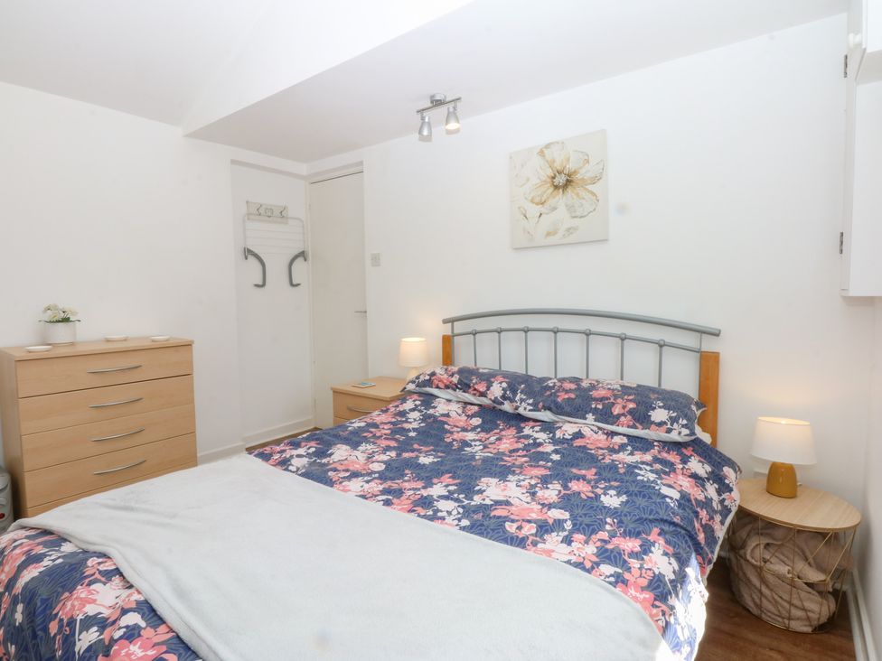 A bedroom with a bed and dresser at Hafan Bach in Abersoch