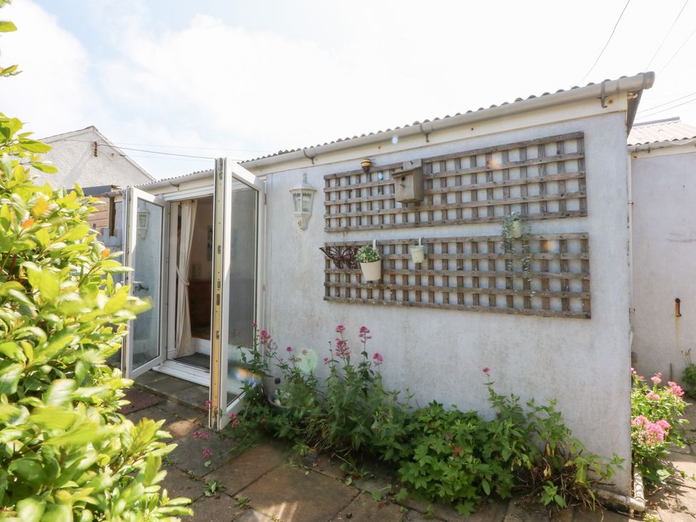 An outdoor space with a door and flower plants at Hafan Bach in Abersoch