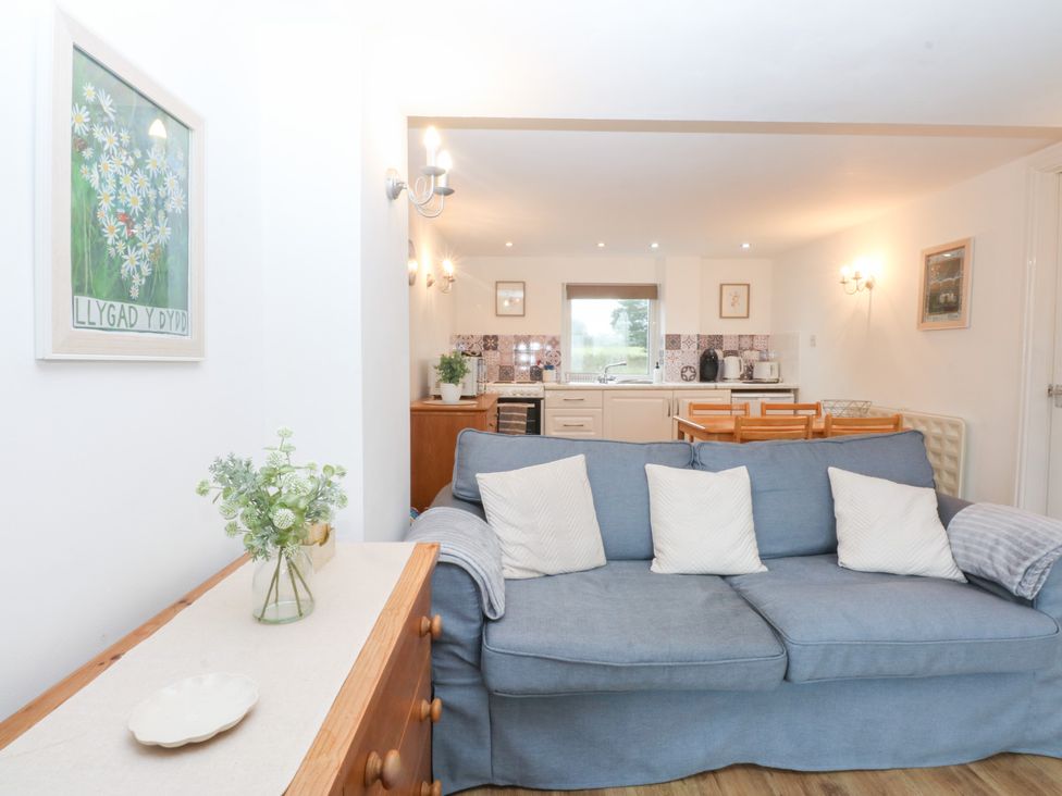 A living room with a sofa and kitchen area at Hafan Bach in Bwlchtocyn near Abersoch