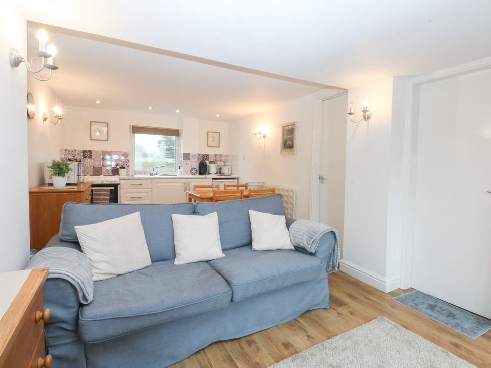 A living room with a sofa and dining area at Hafan Bach in Bwlchtocyn near Abersoch